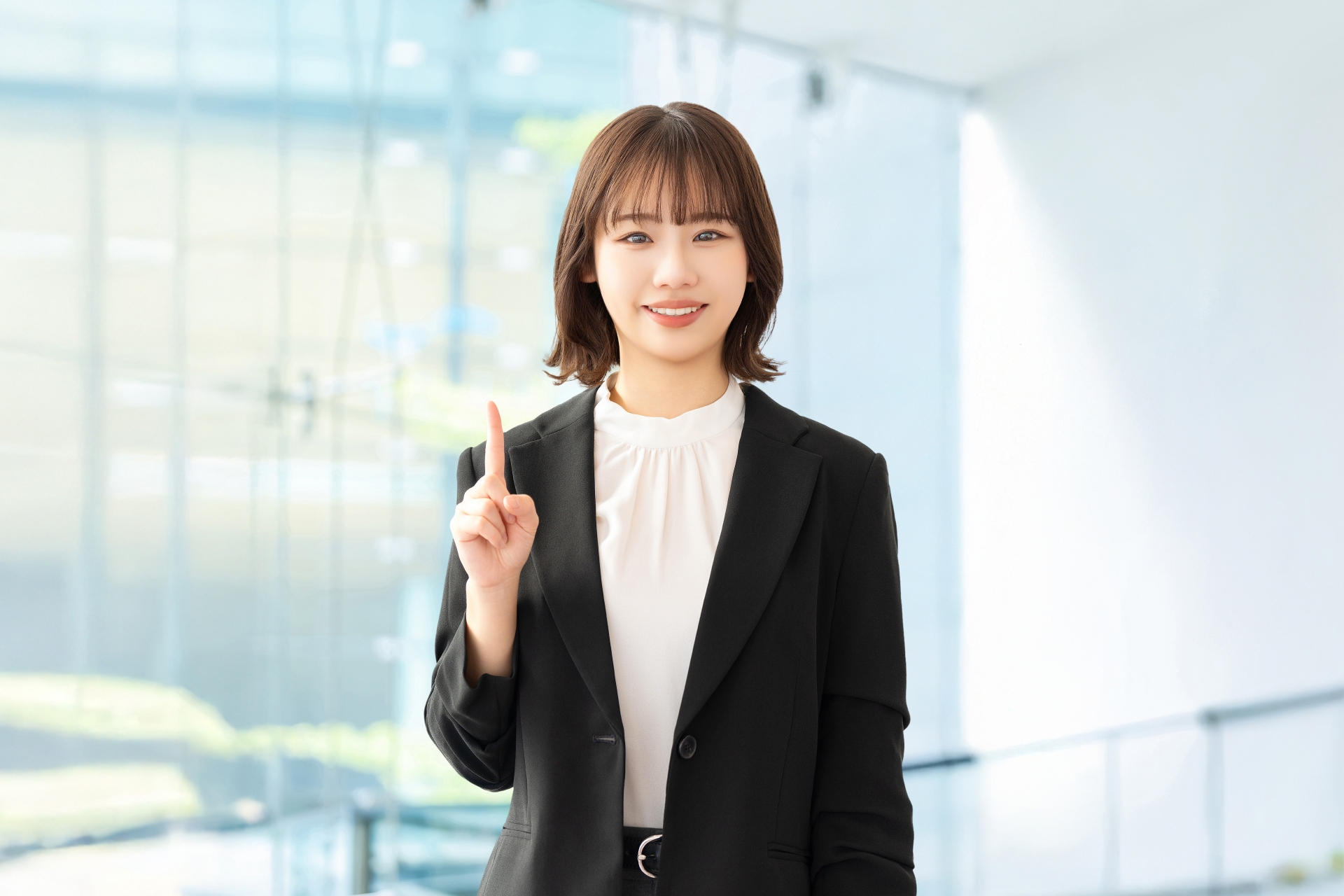 人差し指を立てて案内する笑顔の女性