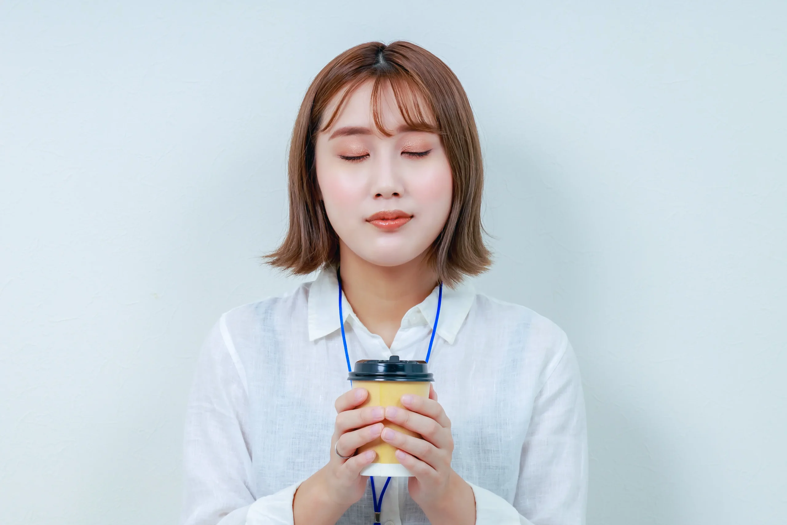 飲み物を手に目を閉じる女性